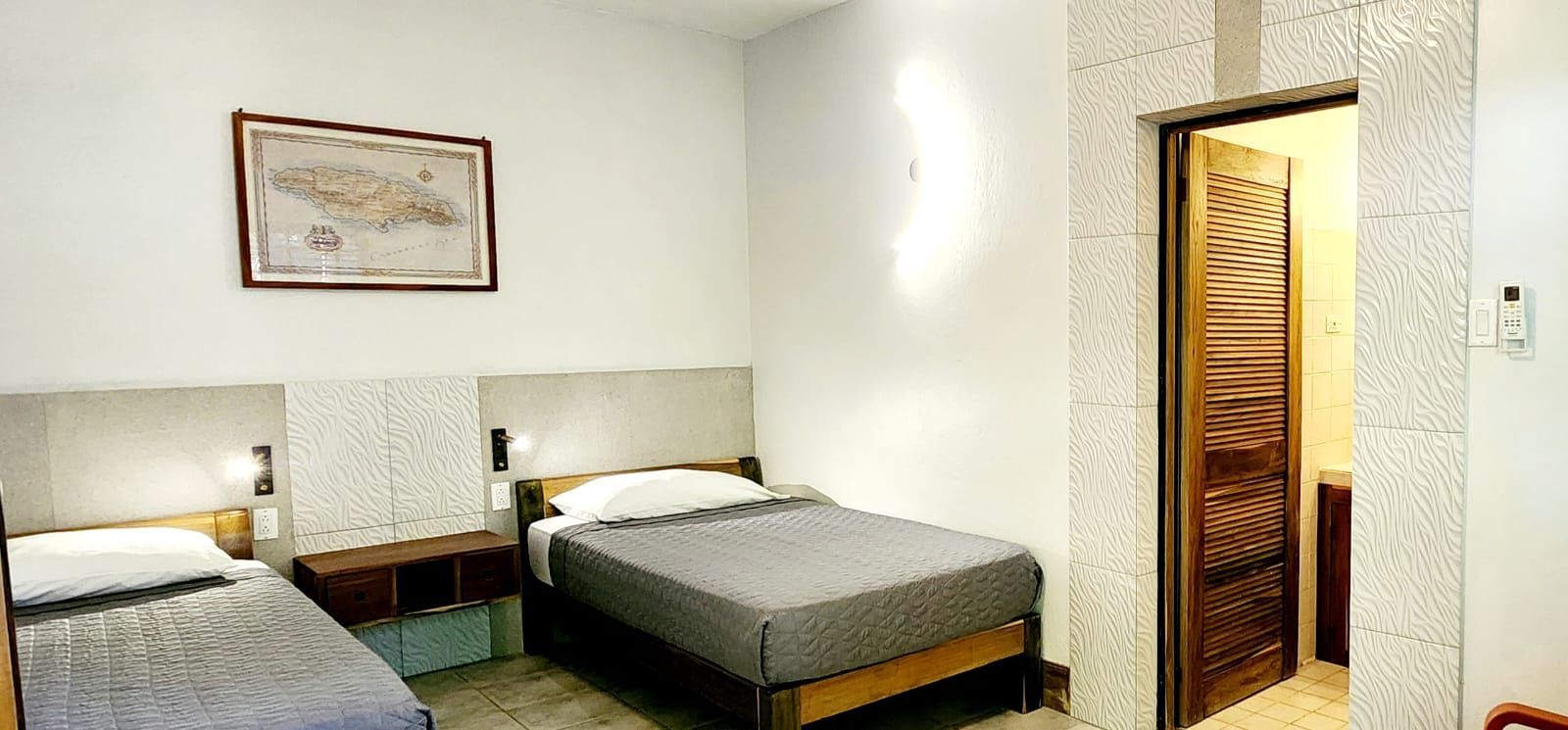 A hotel room with two beds and a door leading to a bathroom.