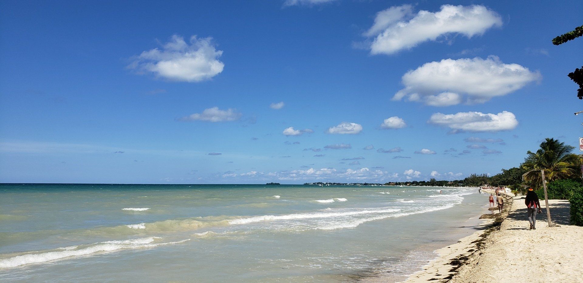 A beach with a blue sky and white clouds in the background