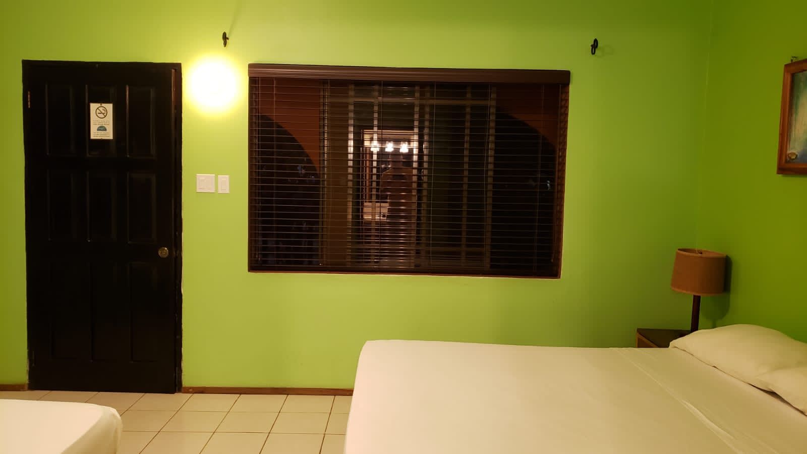 A hotel room with two beds and a green wall.