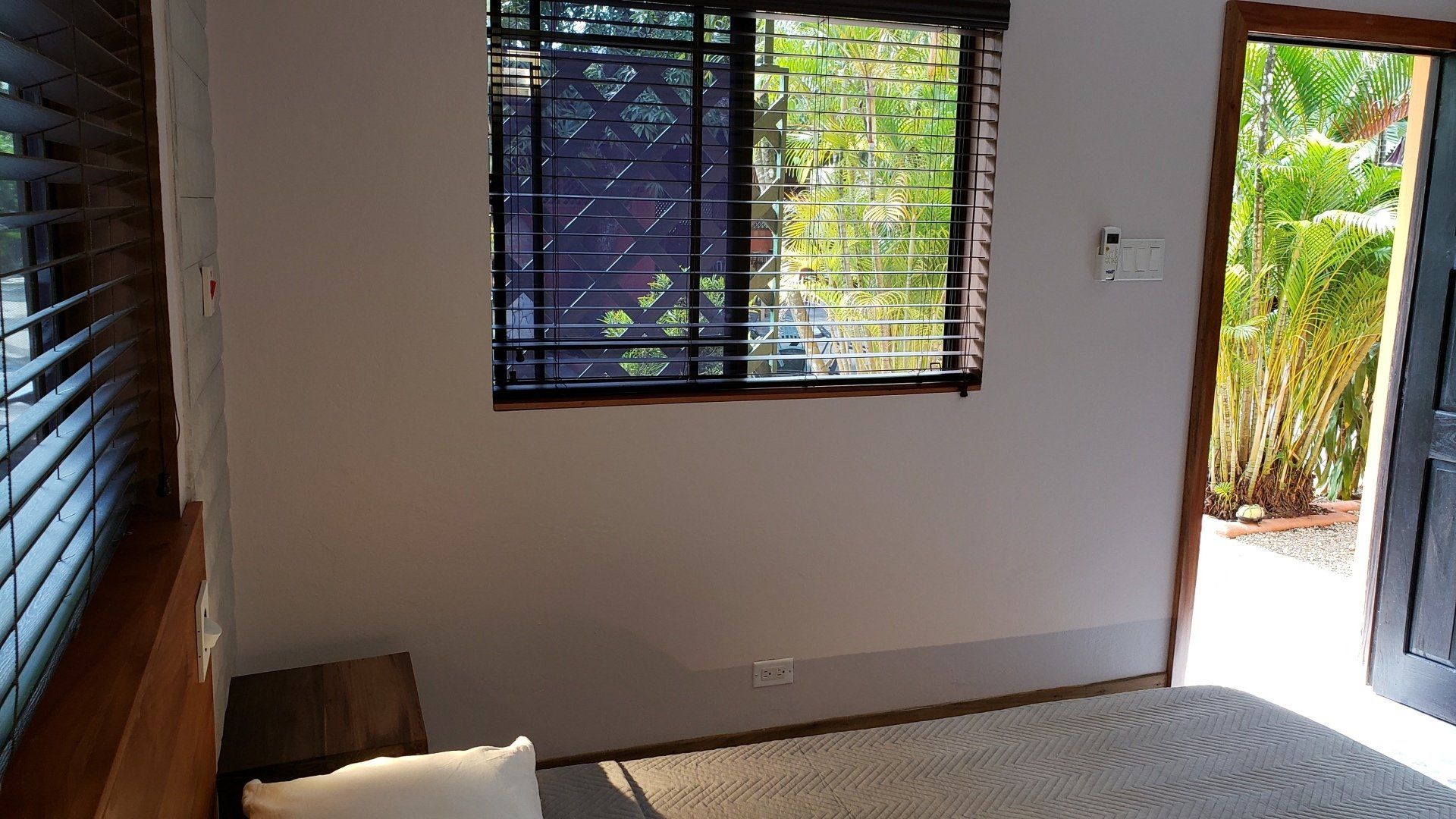 A bedroom with a bed and a window with blinds.