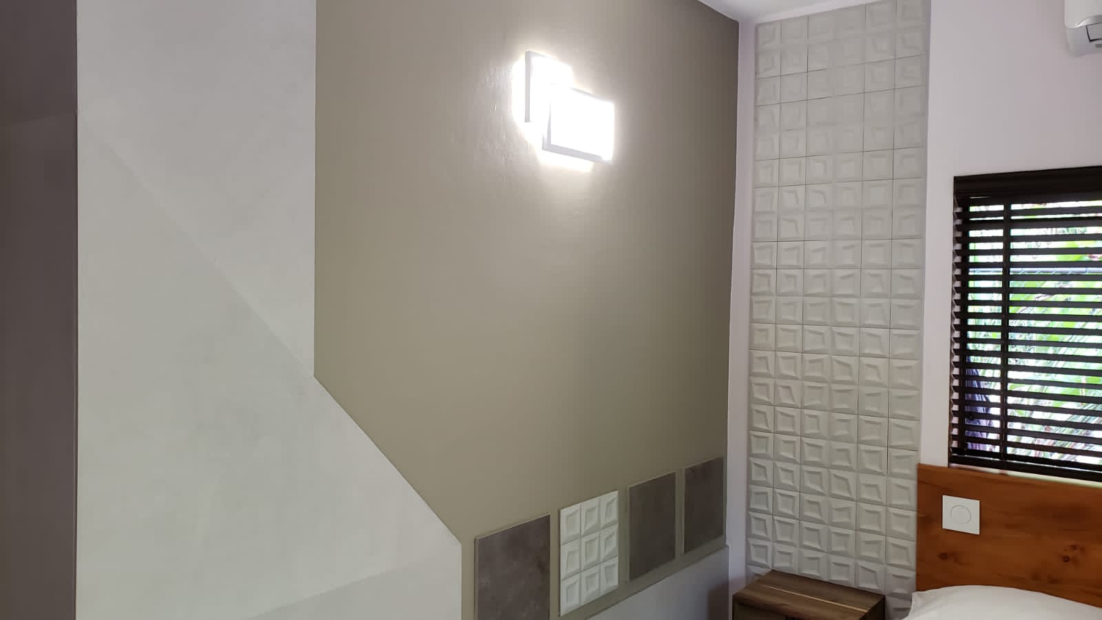 A bedroom with a bed and a window with blinds.