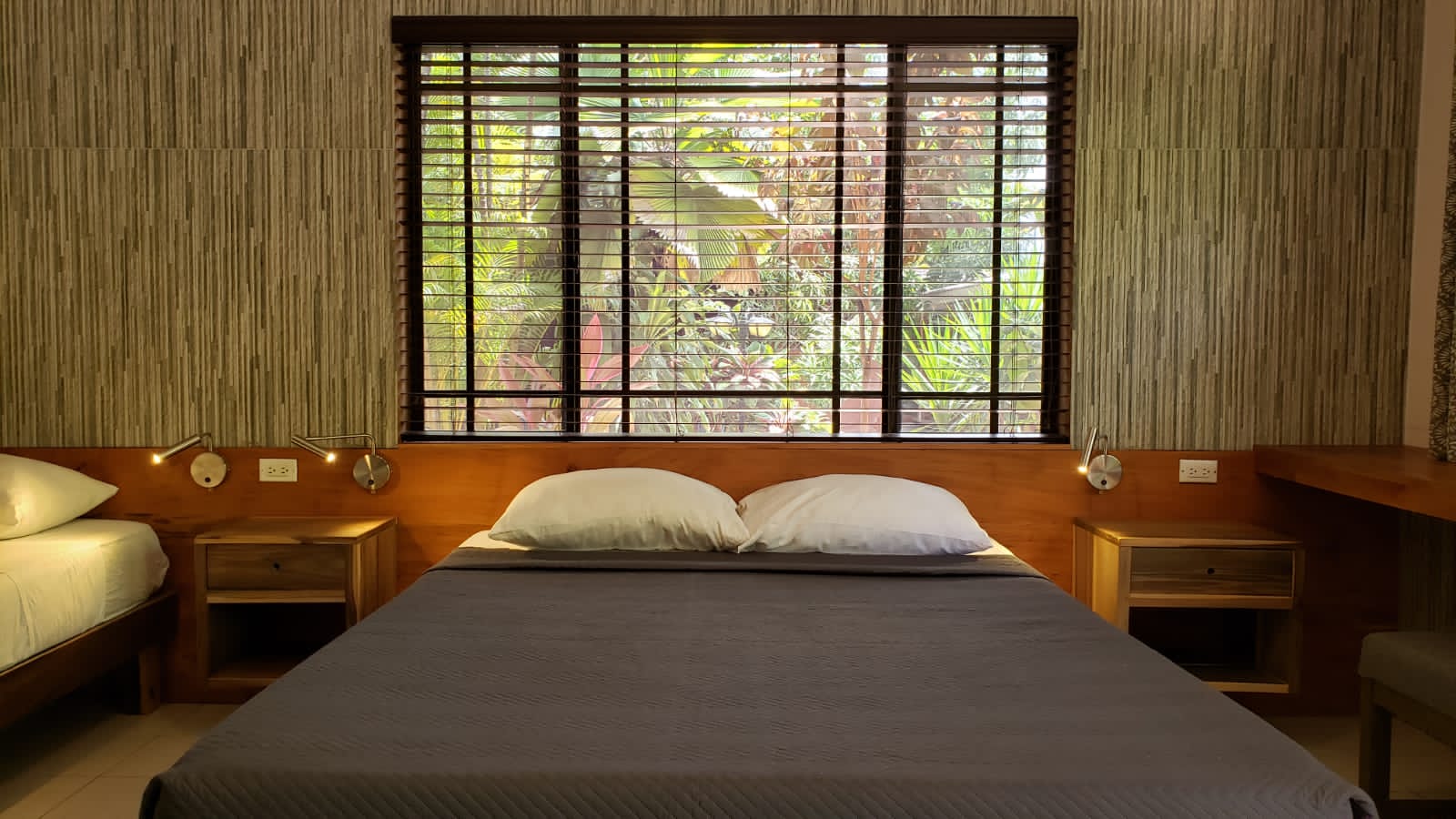 A bedroom with a bed , nightstands , and a window with blinds.