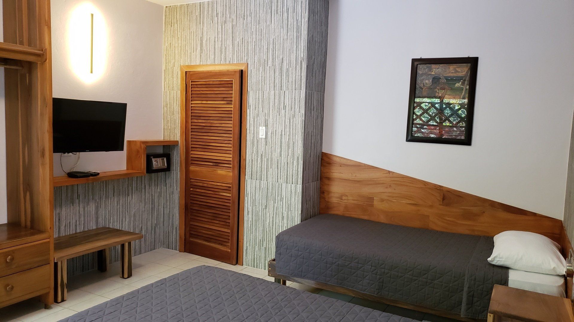 A hotel room with a single bed , a flat screen tv , and a painting on the wall.
