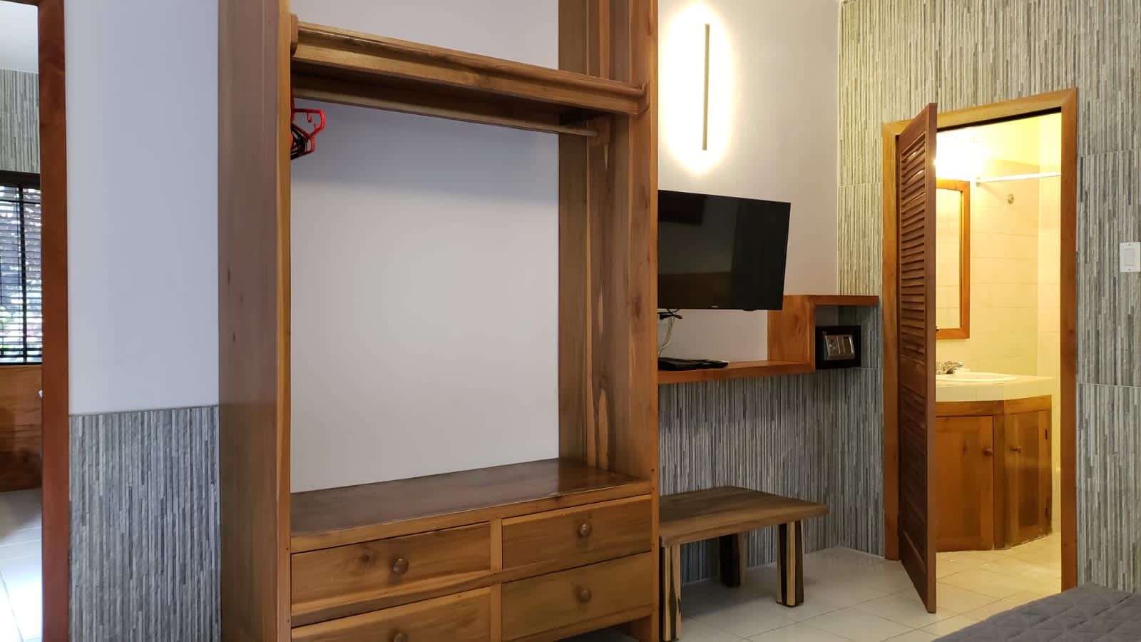 A hotel room with a bed , dresser , and television.