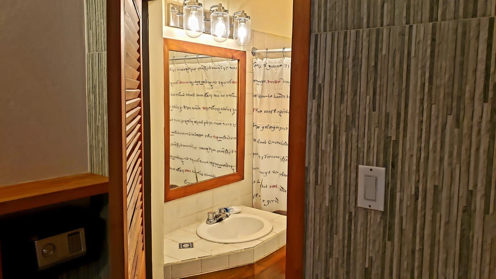 A bathroom with a sink , mirror and shower curtain.