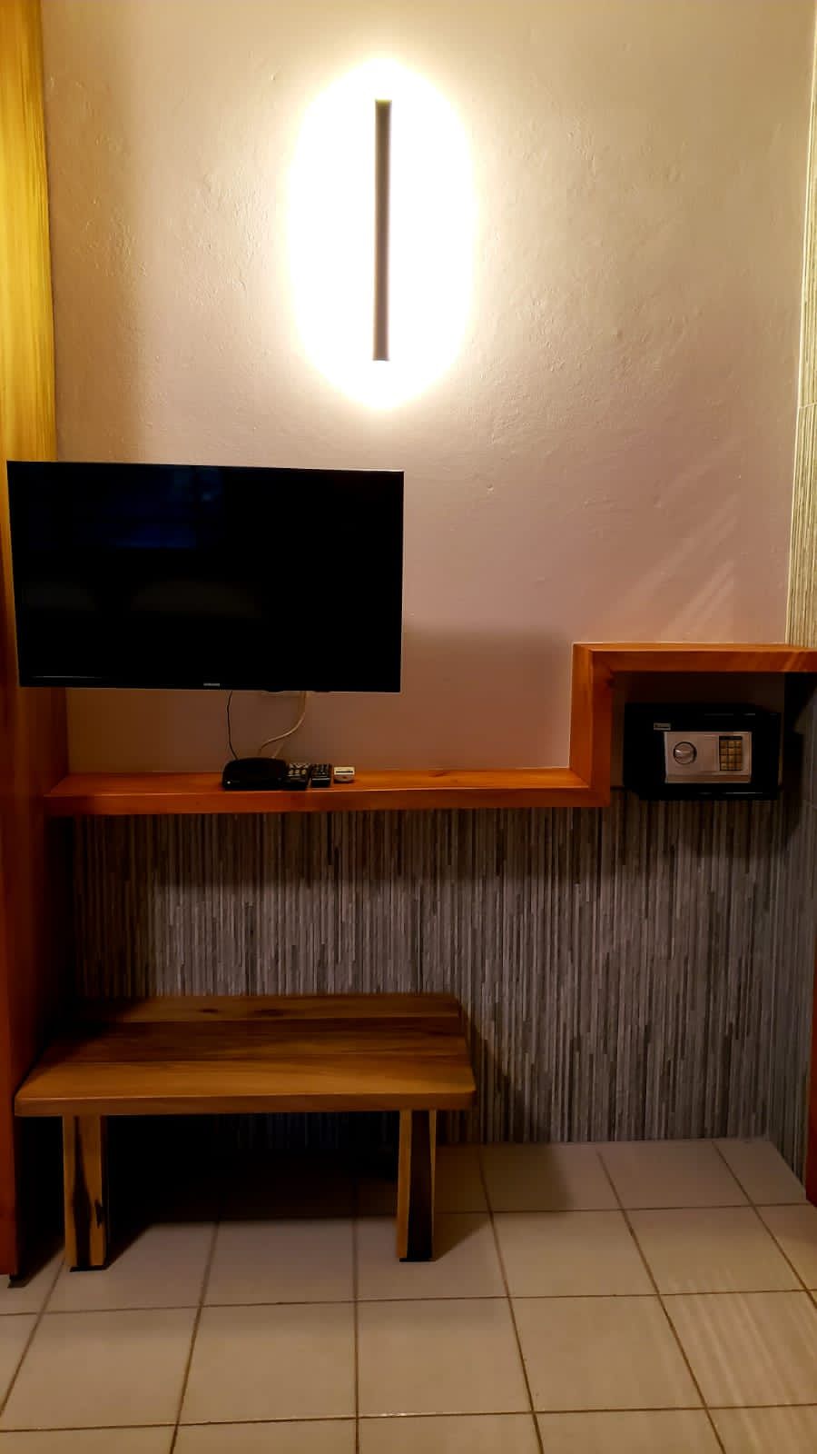 A hotel room with a flat screen tv and a bench.