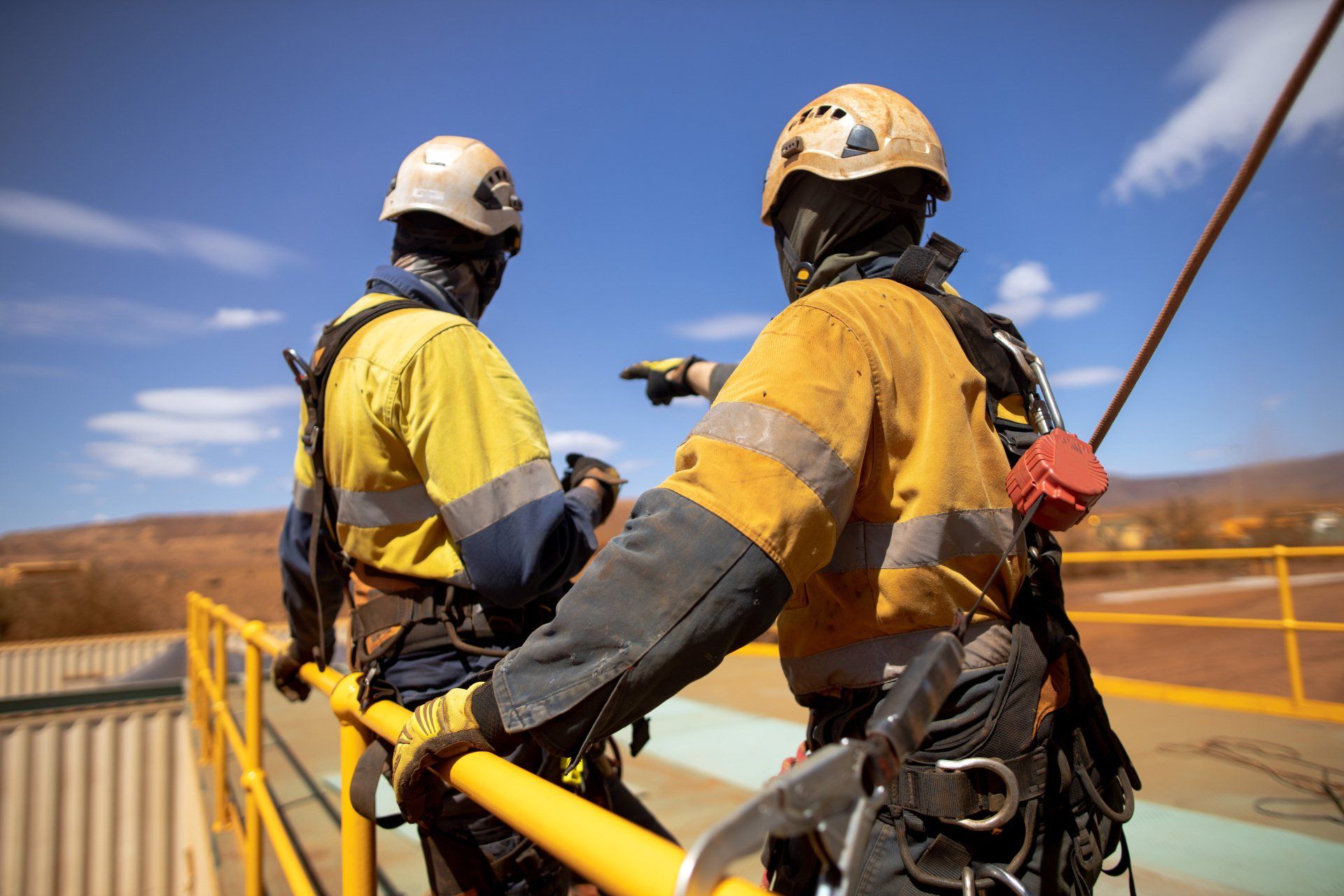 Two men are standing on top of a yellow railing.