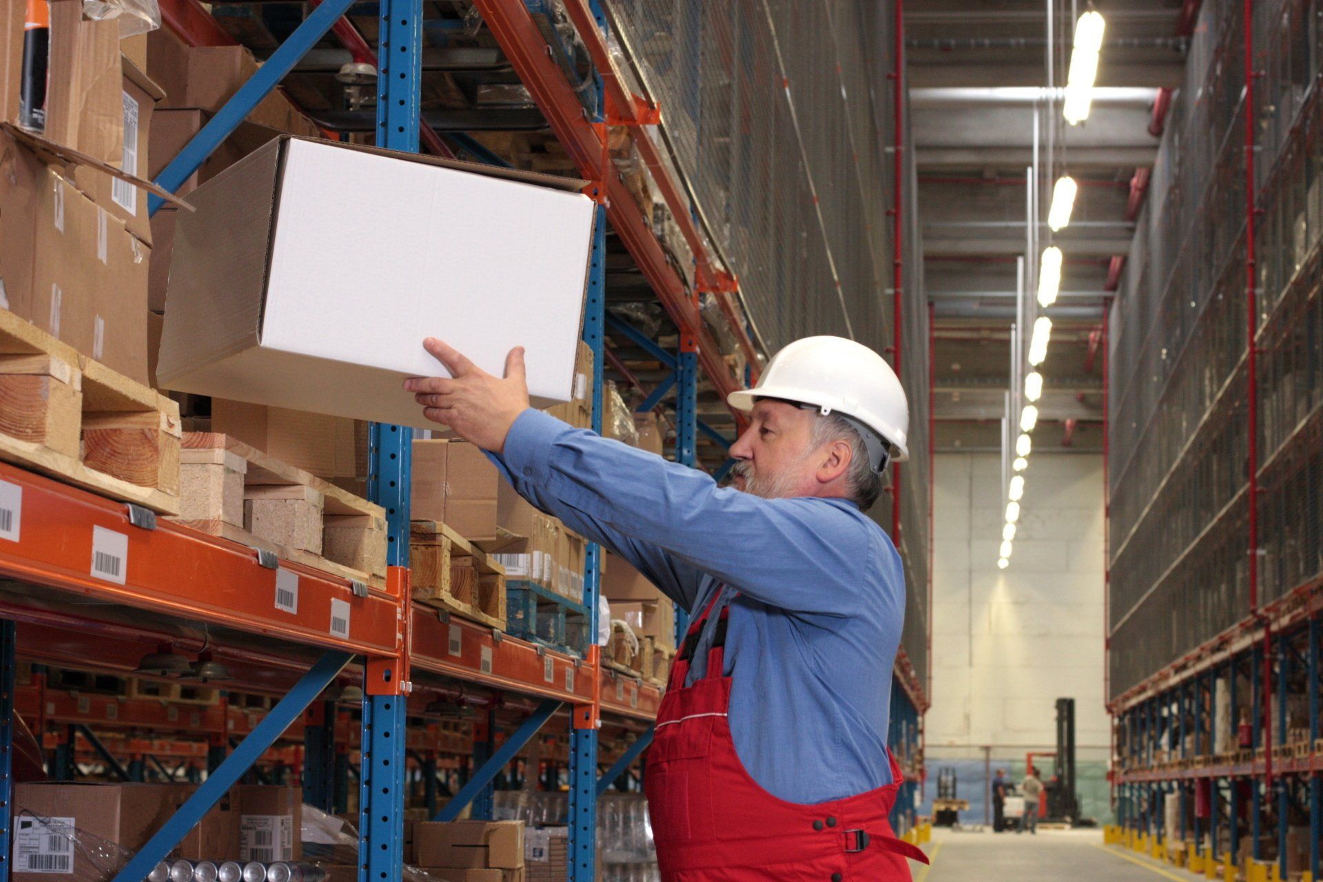 A man is lifting a box in a warehouse.