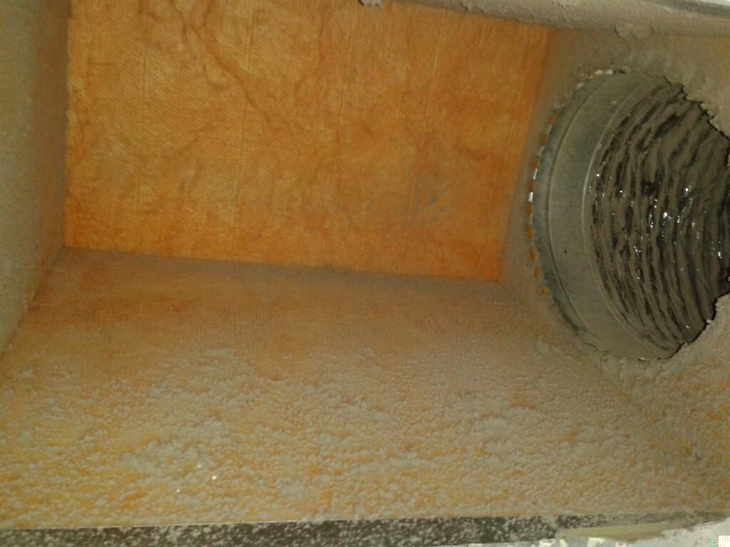 Orange textured interior of a ventilation duct with a metal circular opening on the right