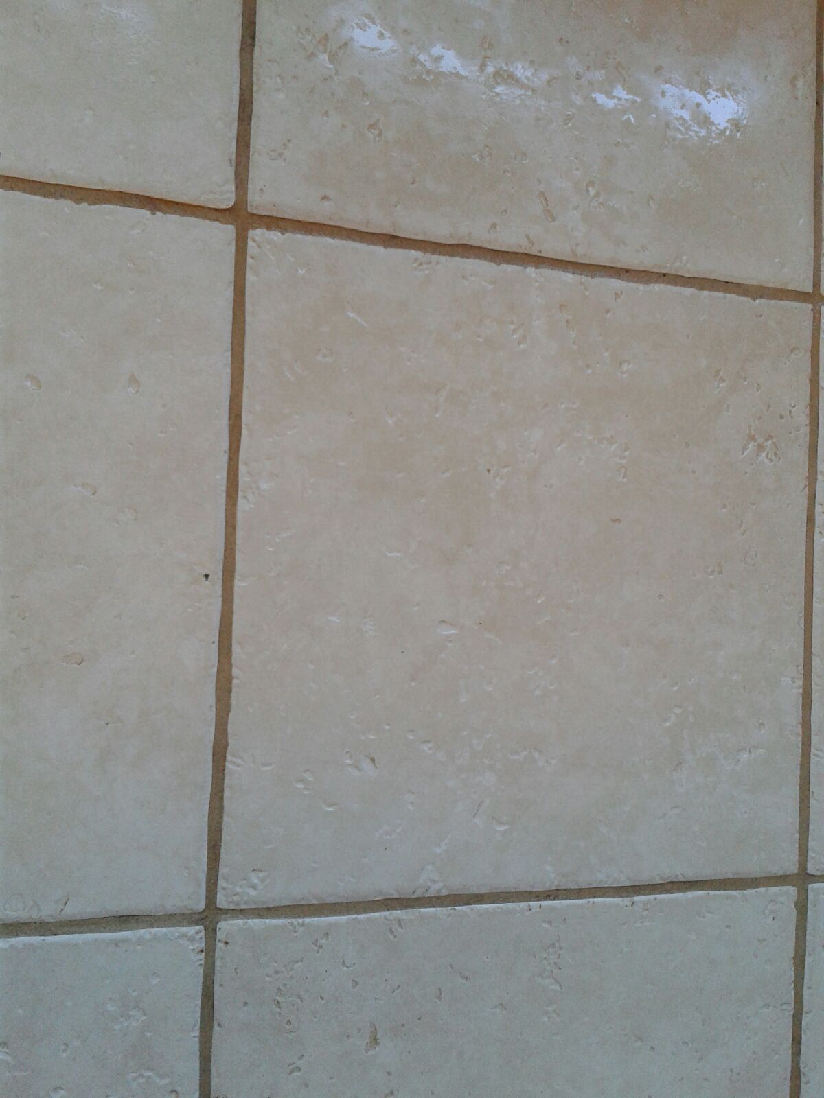 Close-up of beige and light gray ceramic floor tiles with grout lines