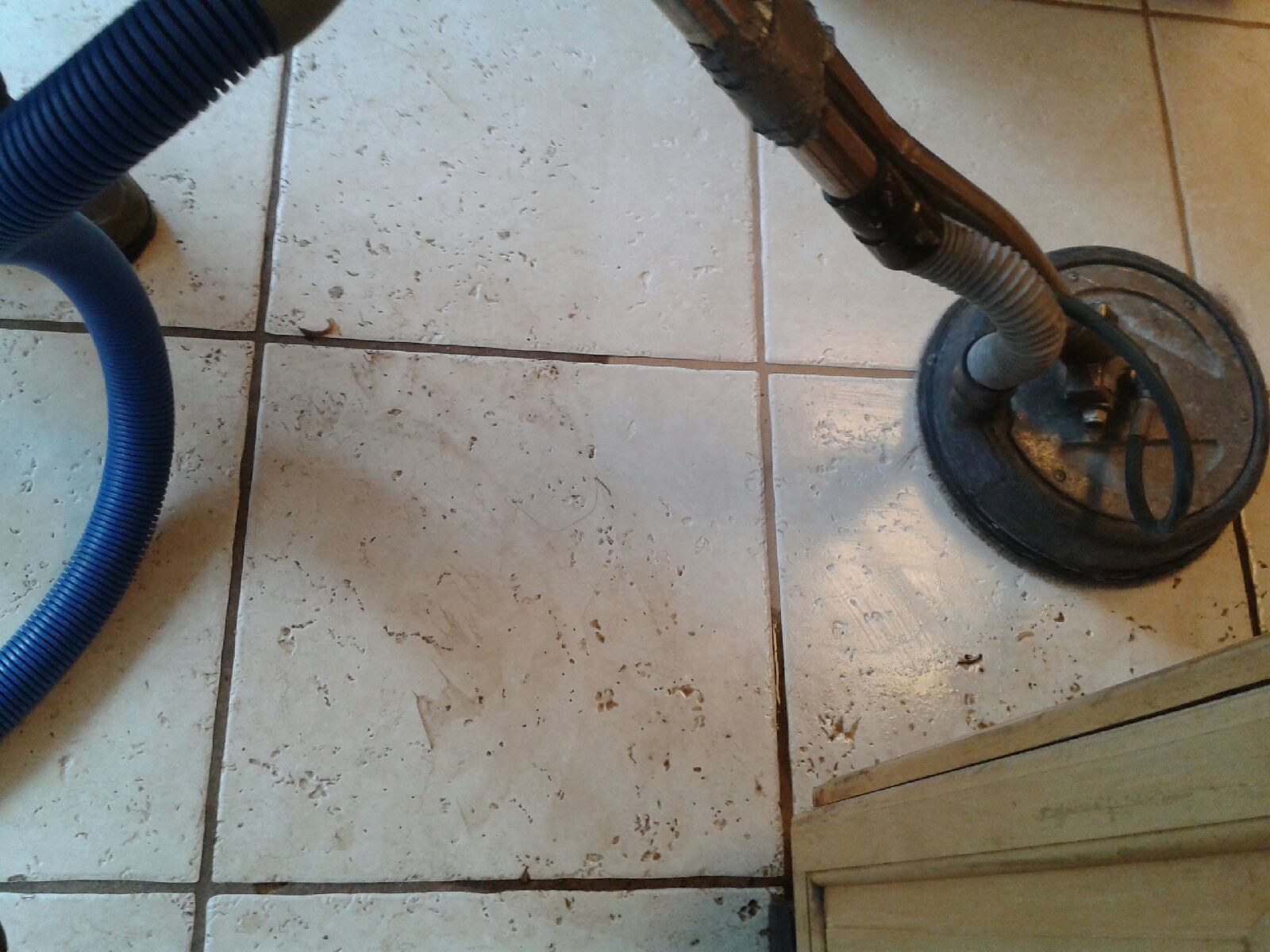 Vacuum cleaner hose and wheel on a dirty tiled floor near a doorway