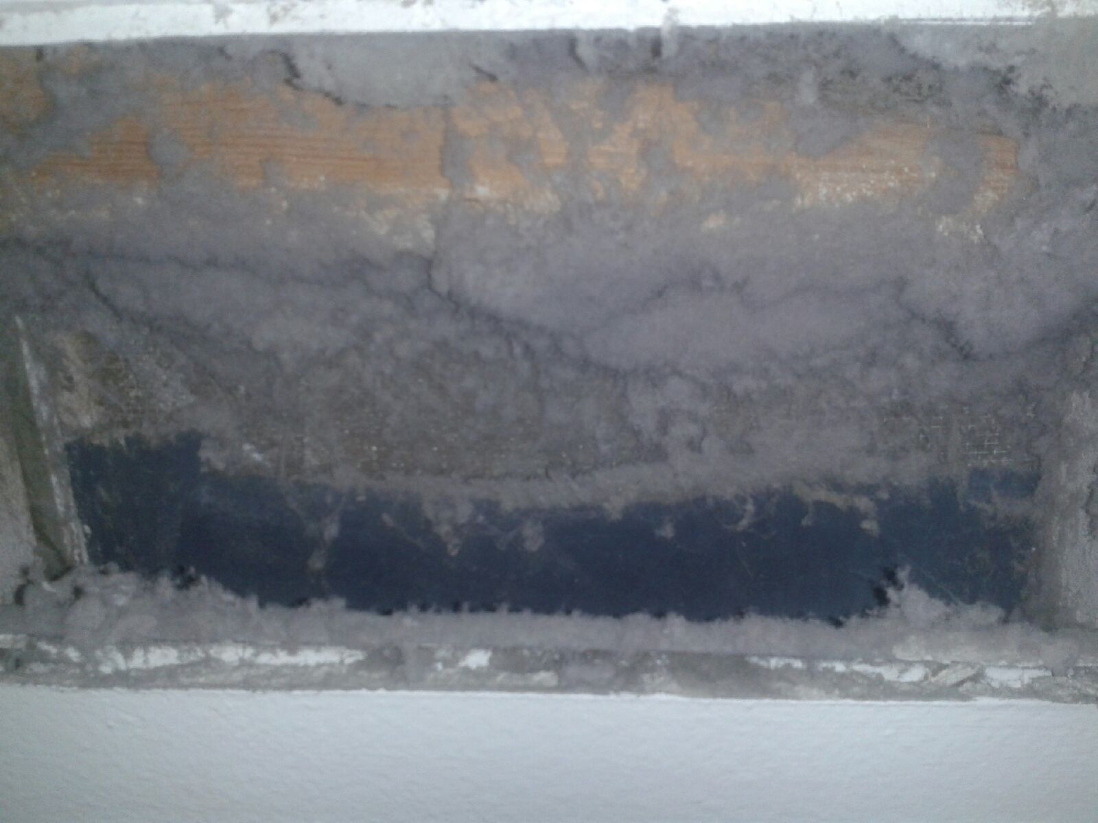 Damaged concrete wall with a dark rectangular opening near the bottom.