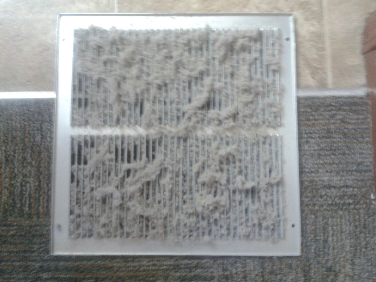 Square white-framed abstract artwork with gray textured patterns on a wall