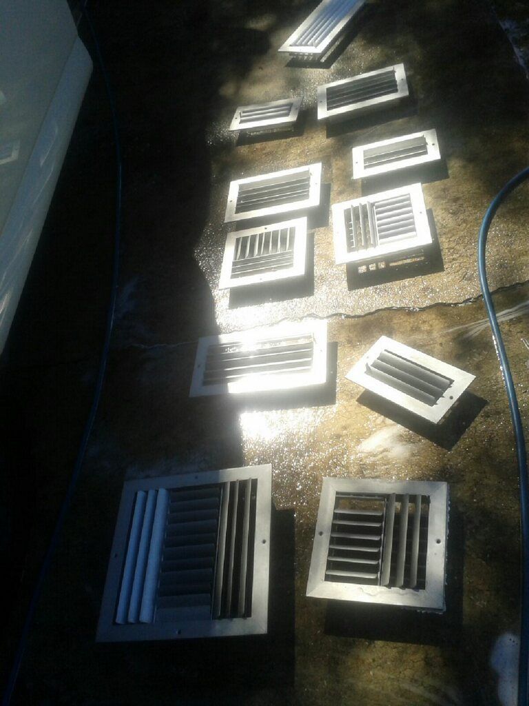 Sunlit floor with several metal air vents and grilles arranged in rows, plus a blue cable on the right.