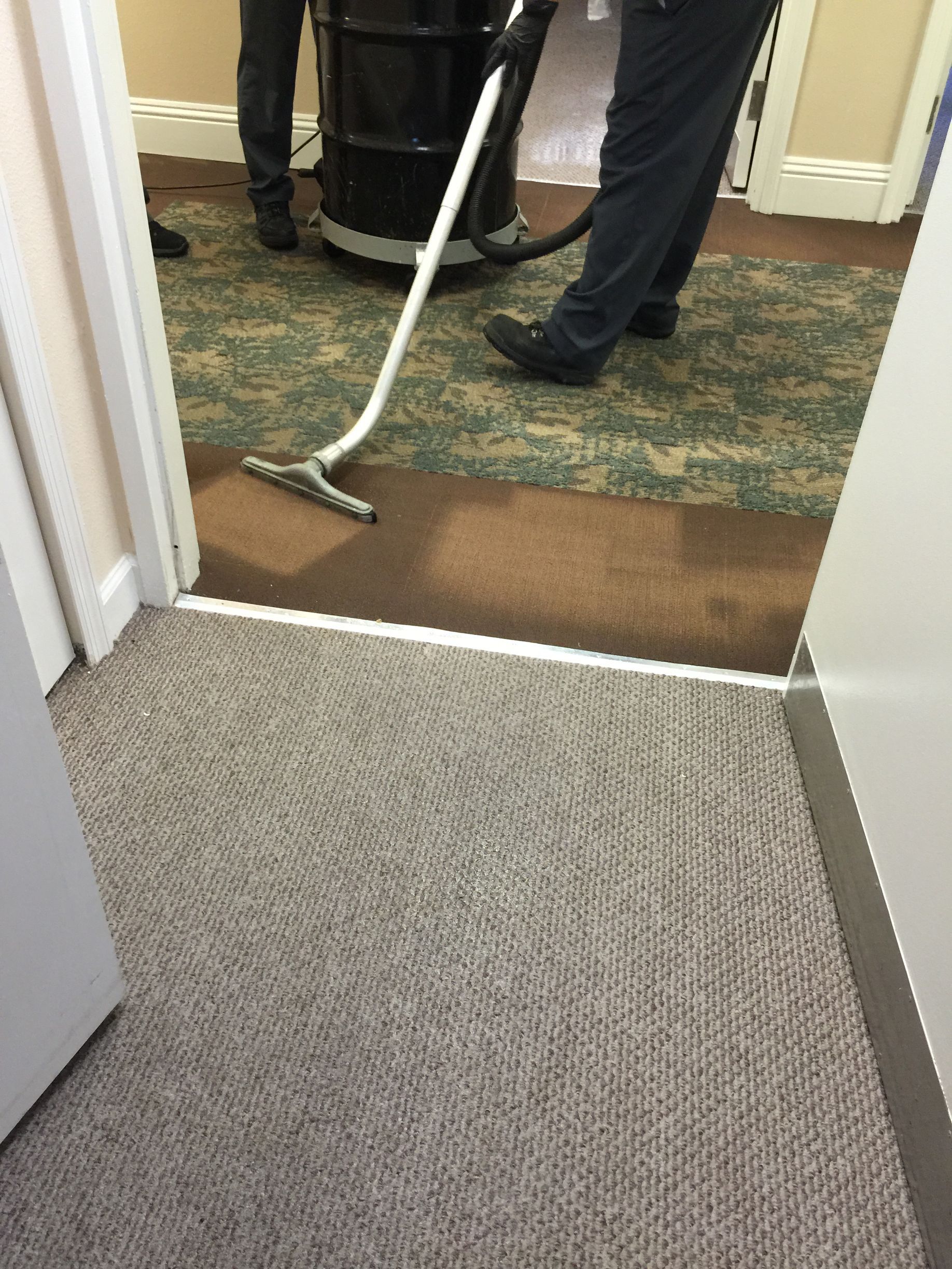 Vacuum cleaning a carpeted hallway at an office doorway