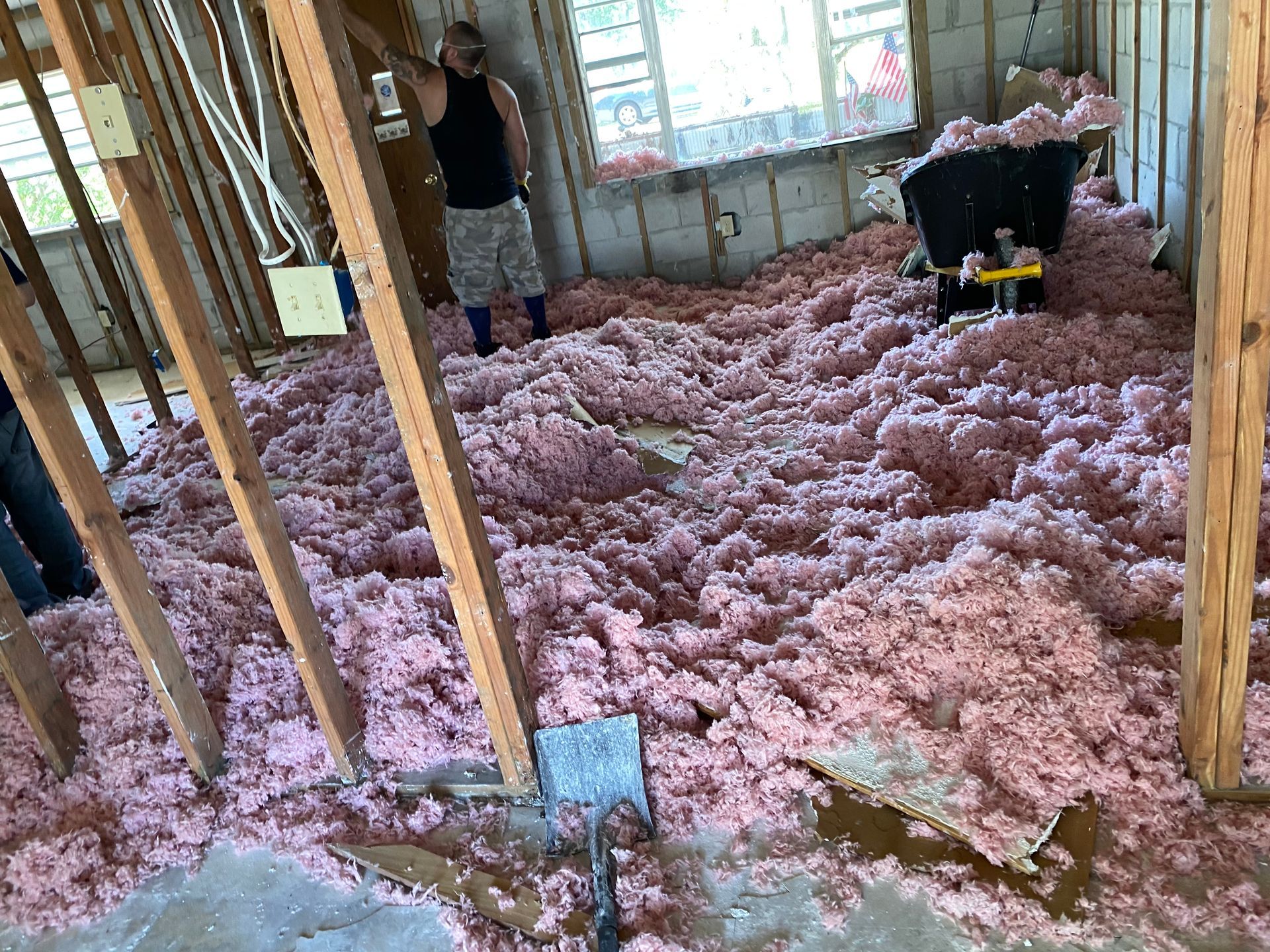 Unfinished room with pink insulation covering the floor and exposed wooden framing.