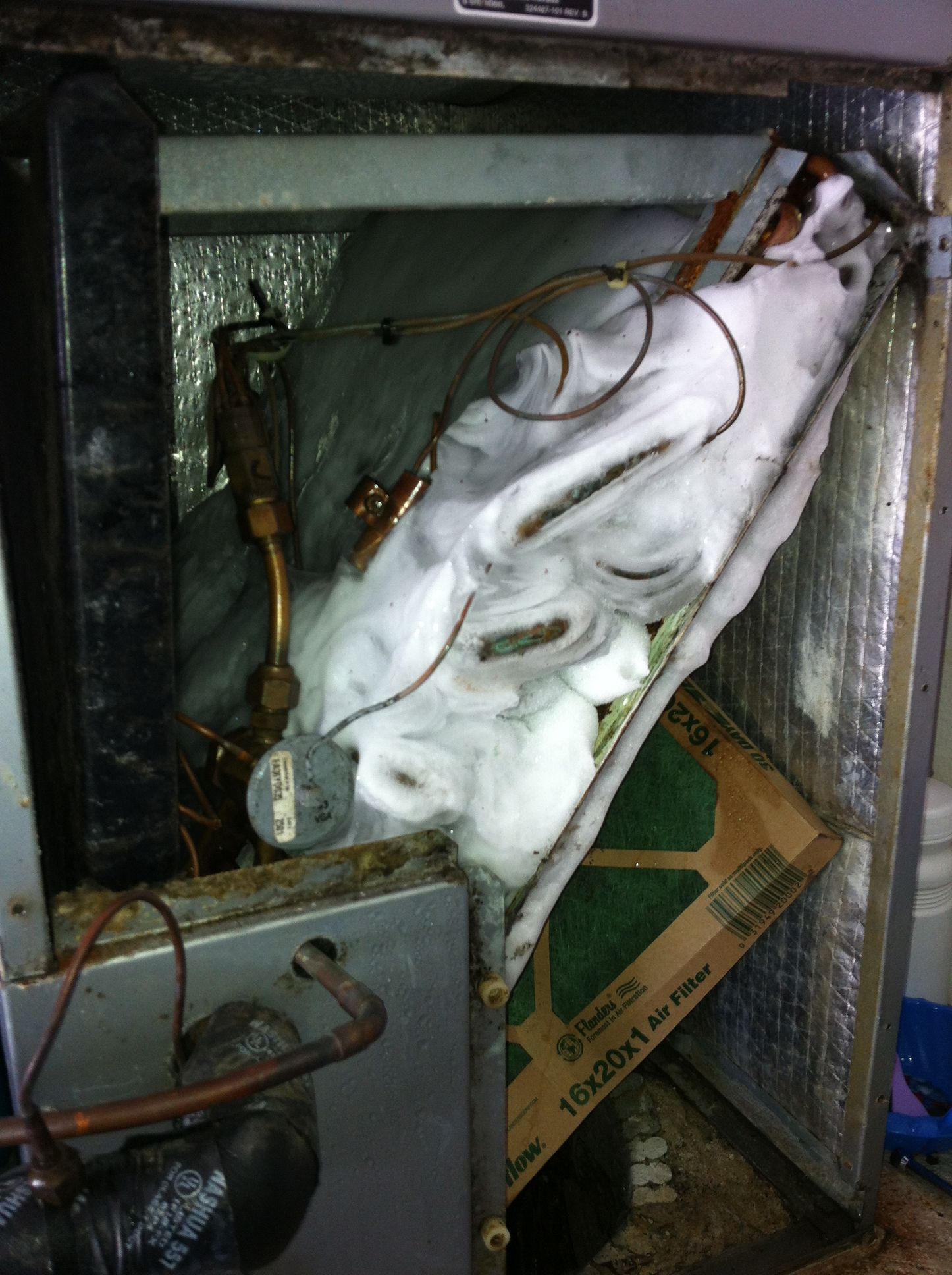 Damaged fridge interior with exposed wires, torn insulation, and a broken lower panel