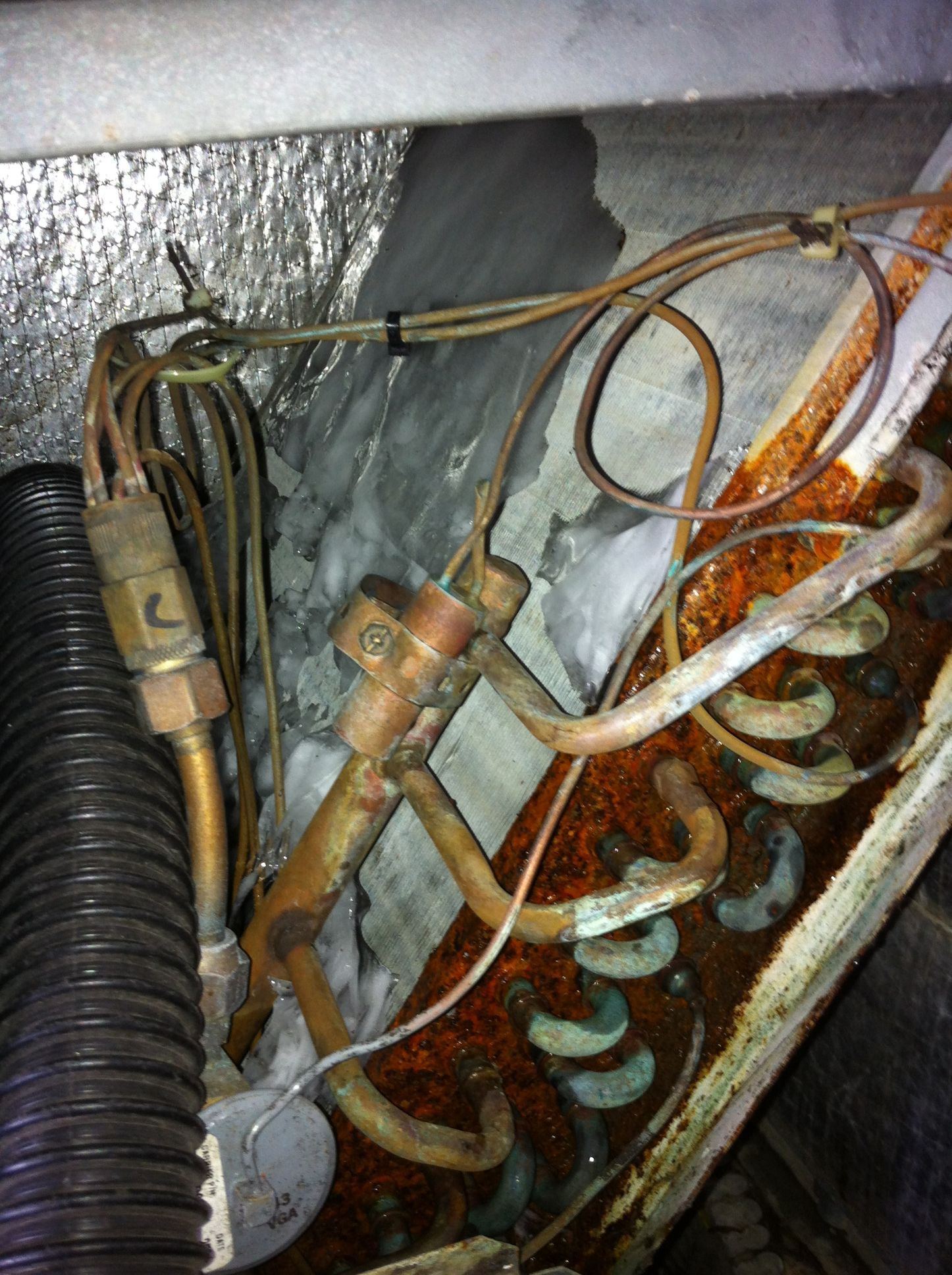 Rusty electrical wiring and corroded components inside a metal appliance panel