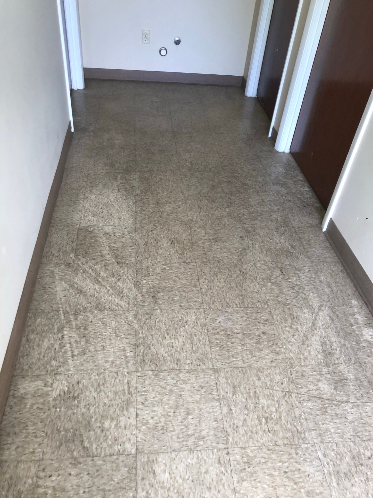 Narrow carpeted hallway with beige walls and doorways on both sides.