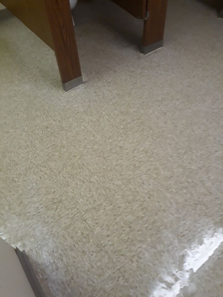 Carpeted floor beneath a wooden table or desk, with bright light reflecting on the lower right corner.