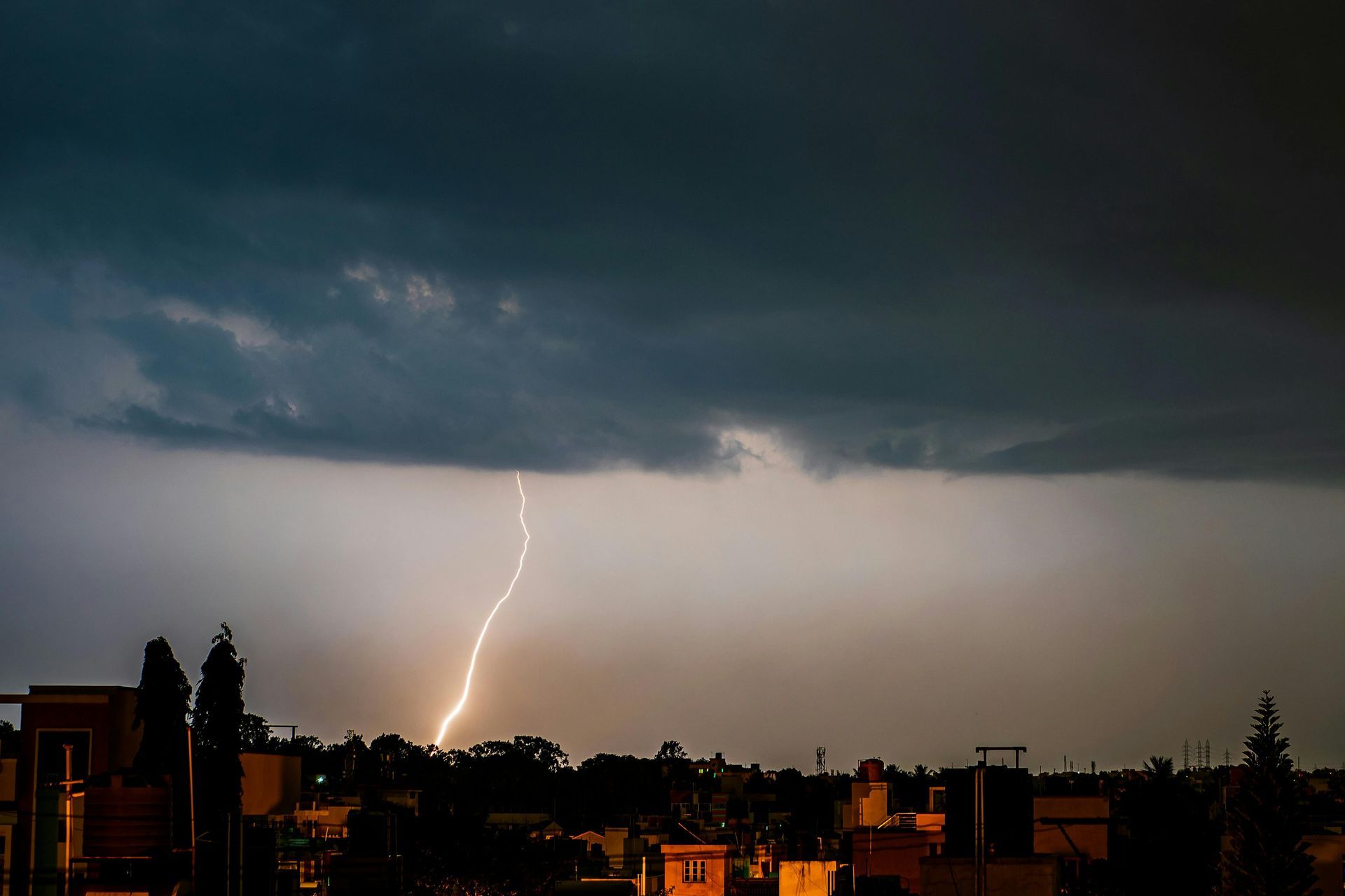 Lightning strikes over a dark city skyline at dusk