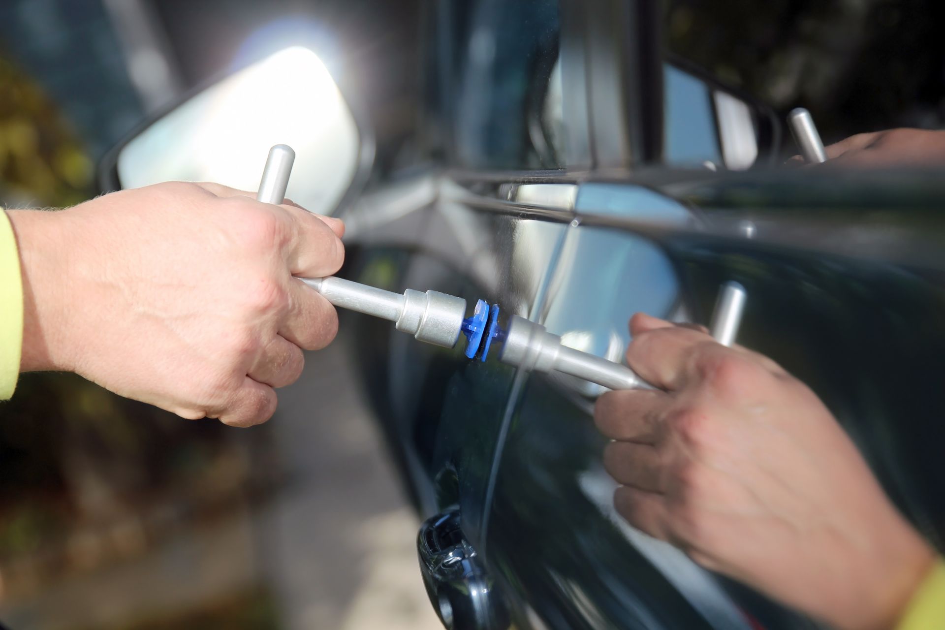 Fixing a dent on a car door with a tool.