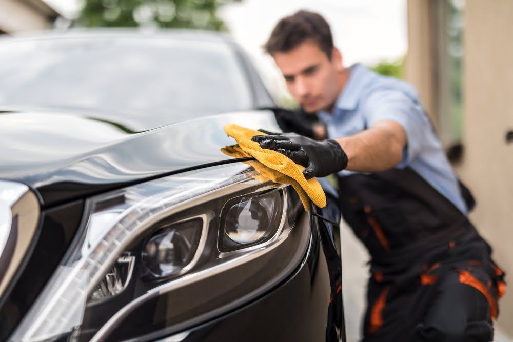 A man using a microfiber cloth to clean a fancy car.