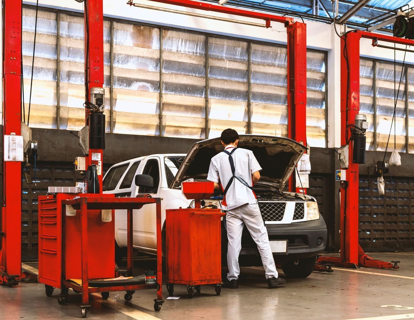 a man is working on a car in an auto body repair garage with the hood up