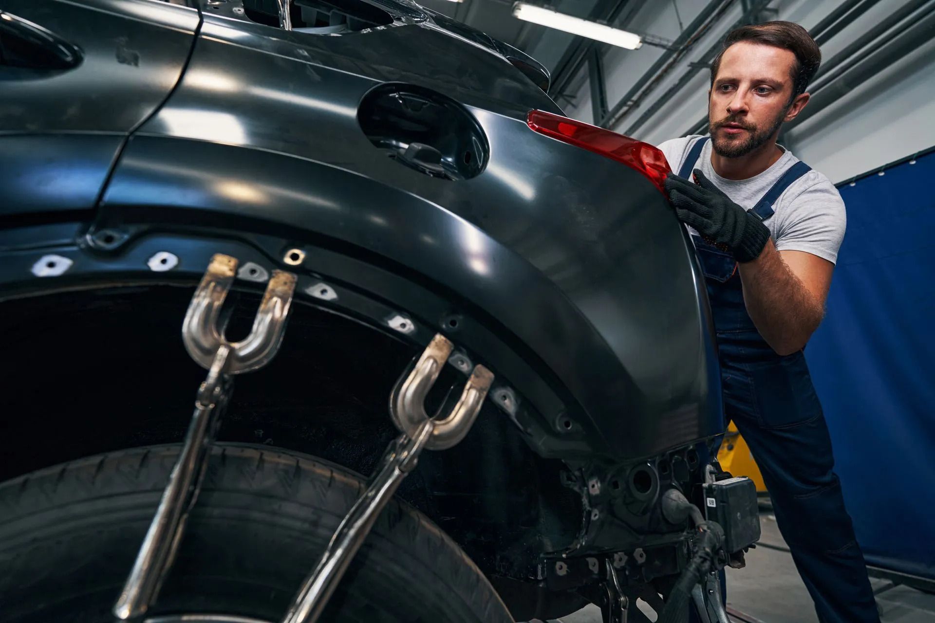 A man is working on the back of a car in a garage leaning how frame straightening works