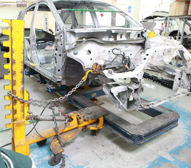 A man wearing a mask is working on a car in a garage.