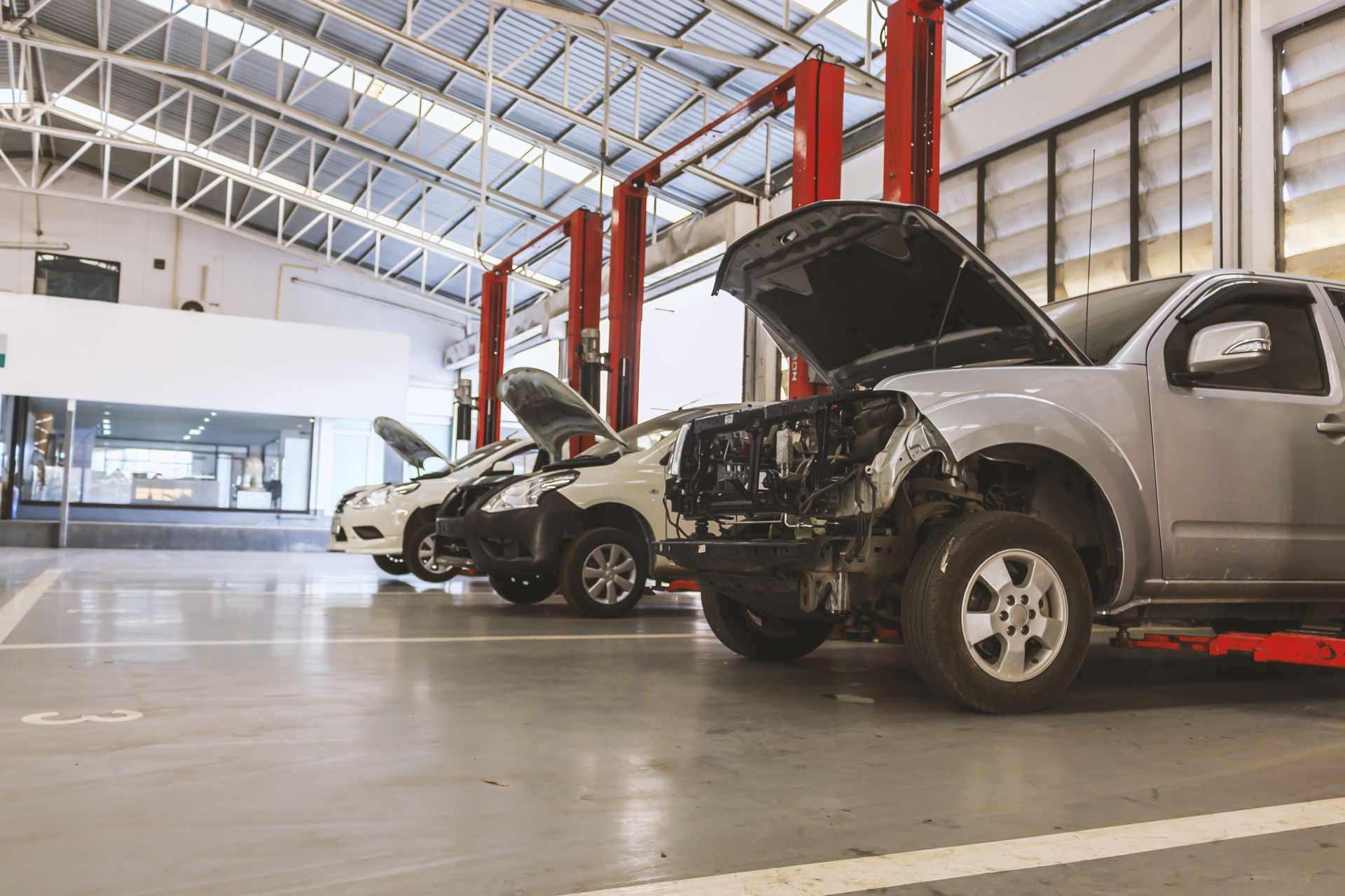 a row of cars with their hoods open in an auto body repair garage