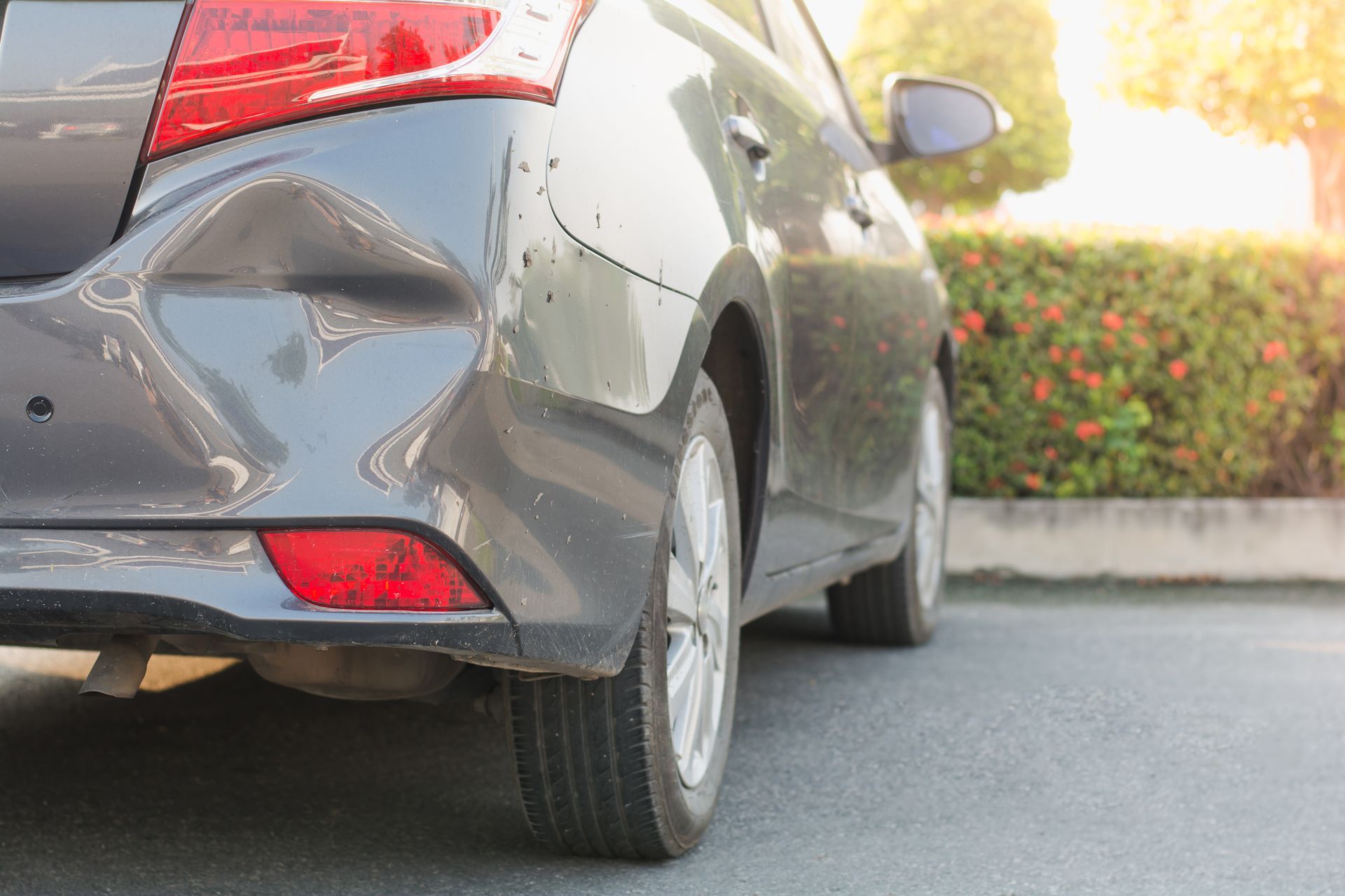 A car with a damaged bumper is parked on the side of the road.