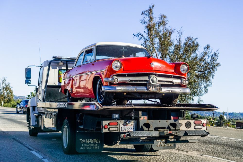 A red car is being towed by a tow truck.