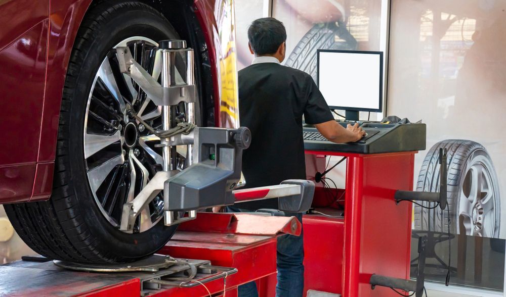 A man is adjusting a tire on a machine in a garage.