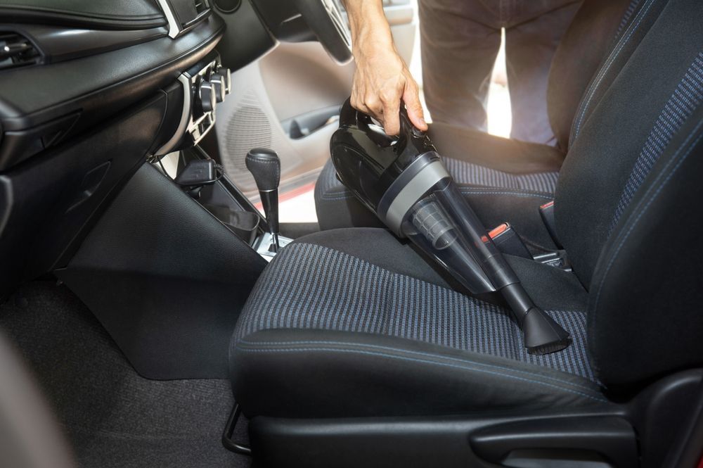 man vacuuming his car seat in an attempt to get a stain out