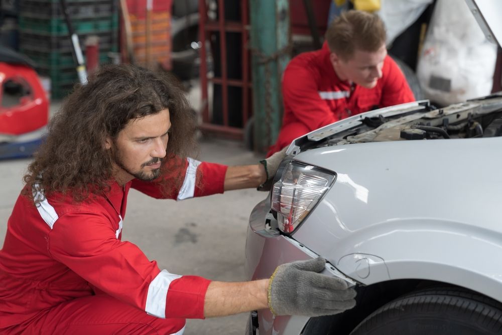 mechanics doing an auto frame repair on a car