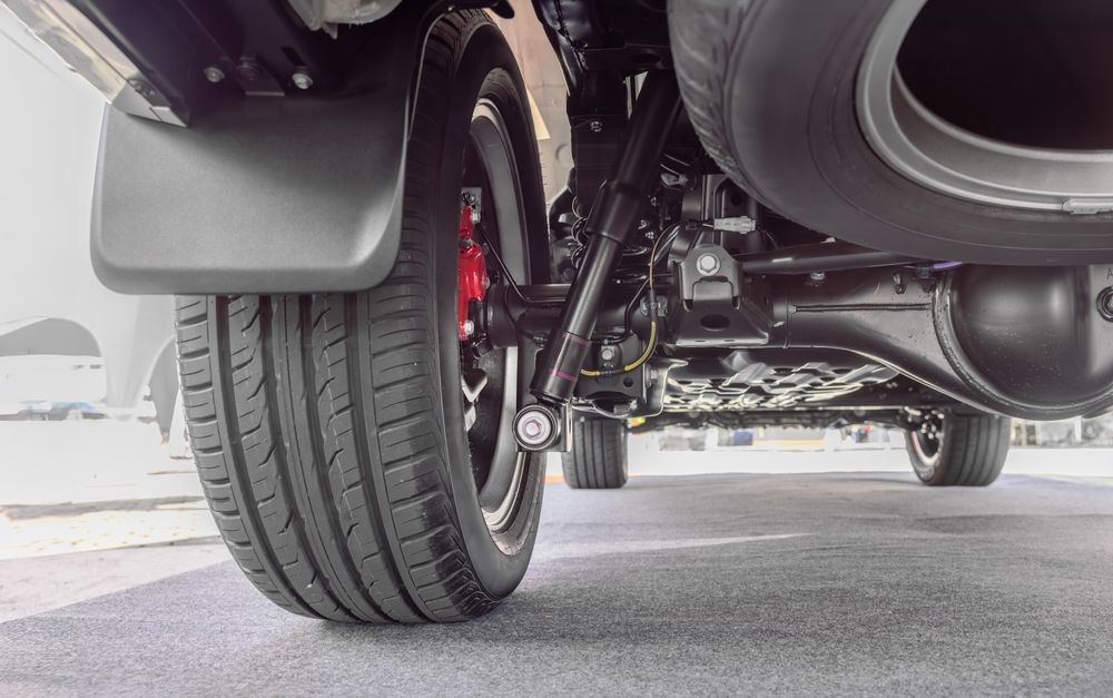 A close up of the underside of a car with a tire and exhaust pipe.