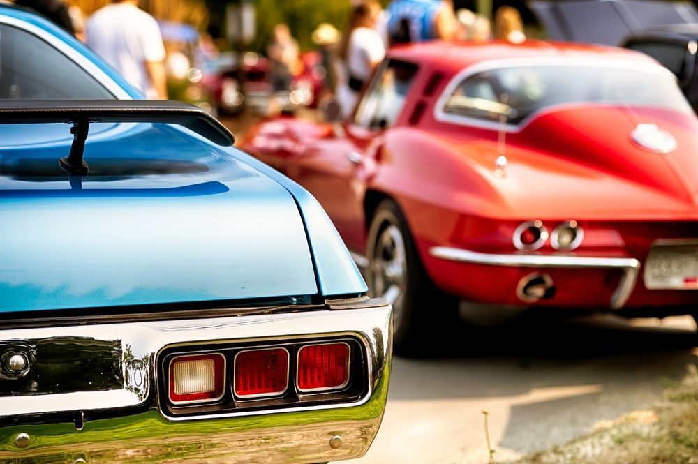 A blue car is parked next to a red car at a car show.