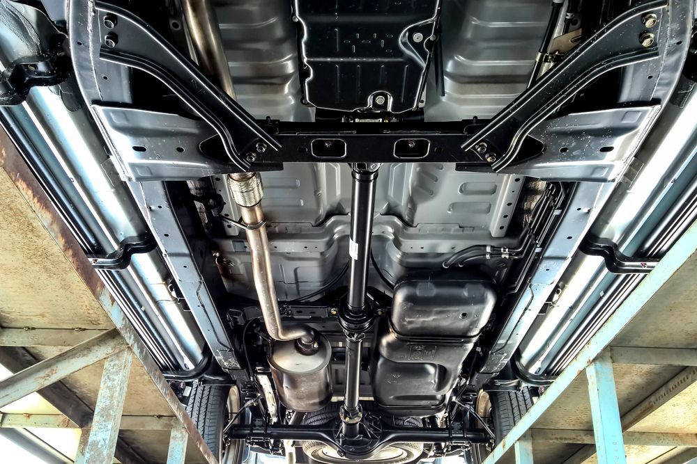 The underside of a car is shown in a garage.