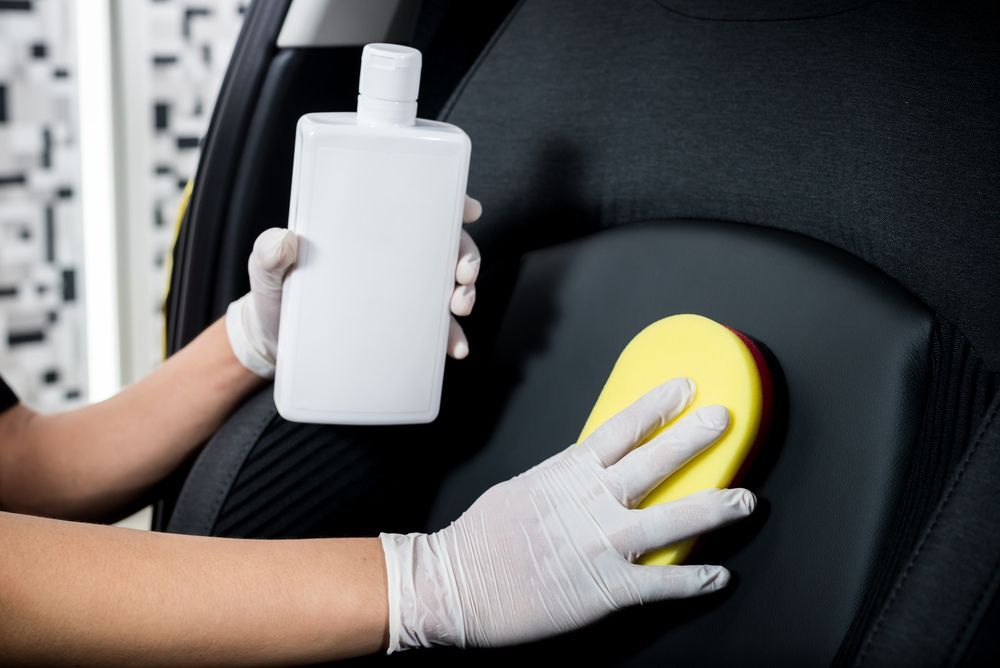 person cleaning their car seat stain with a store-bought solution