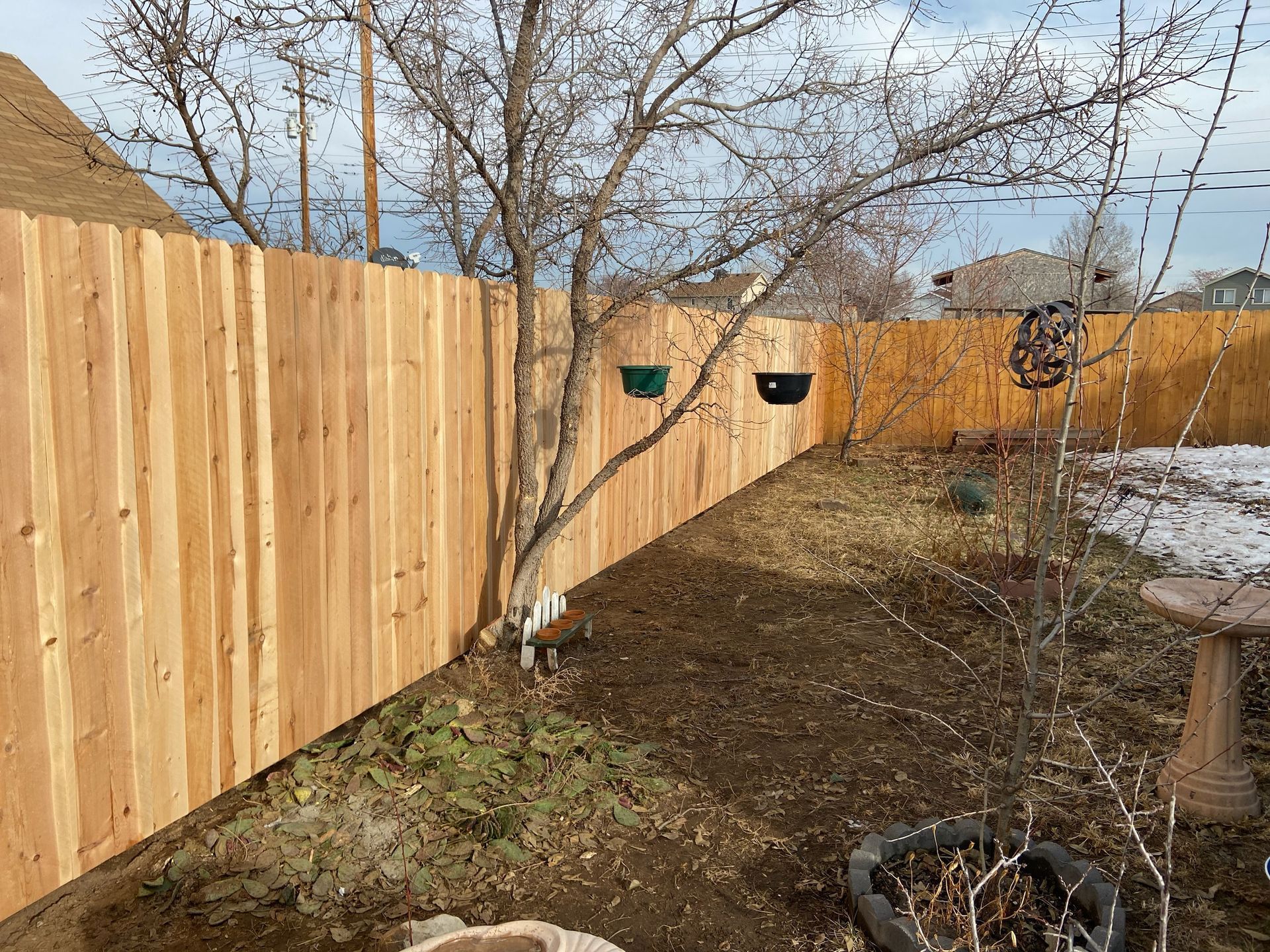 A wooden fence is in the backyard of a house.