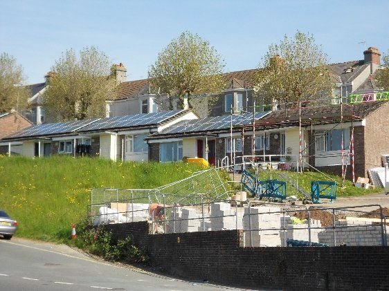Apollo Electrical Solutions | A row of houses with solar panels on the roofs