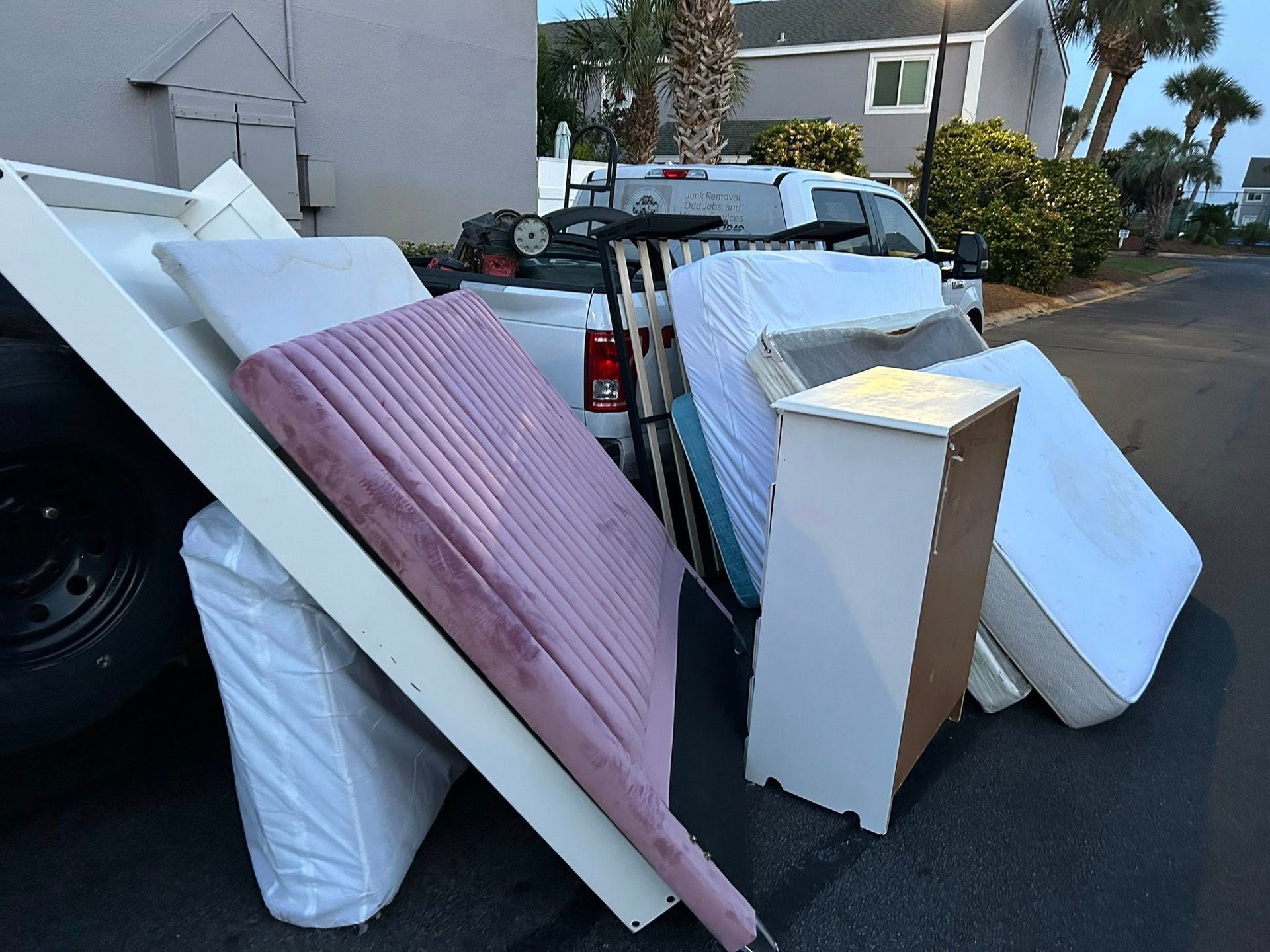 Pickup truck overflowing with mattresses, furniture, and other discarded items.