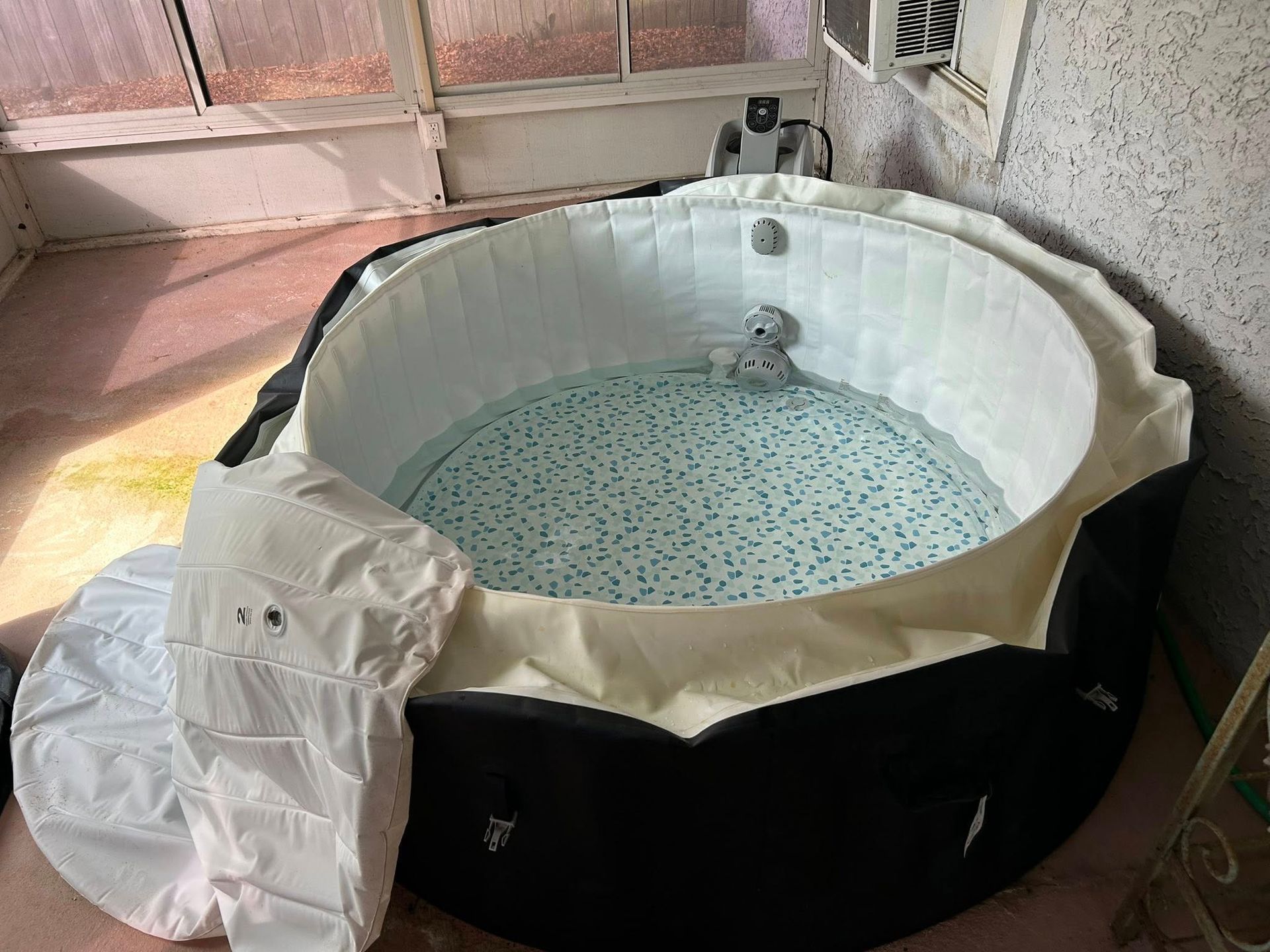 An inflatable round hot tub with a teddy bear inside, set indoors.