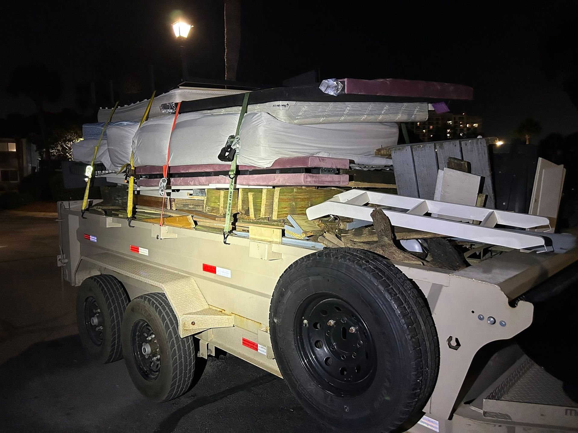 Tan trailer loaded with debris at night.