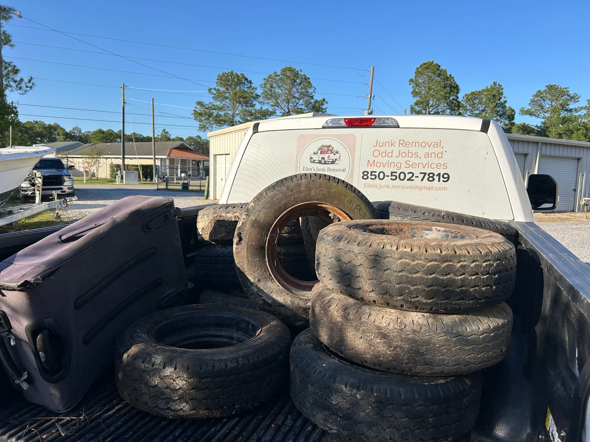 Truck bed with tires and a travel case, parked near a building.