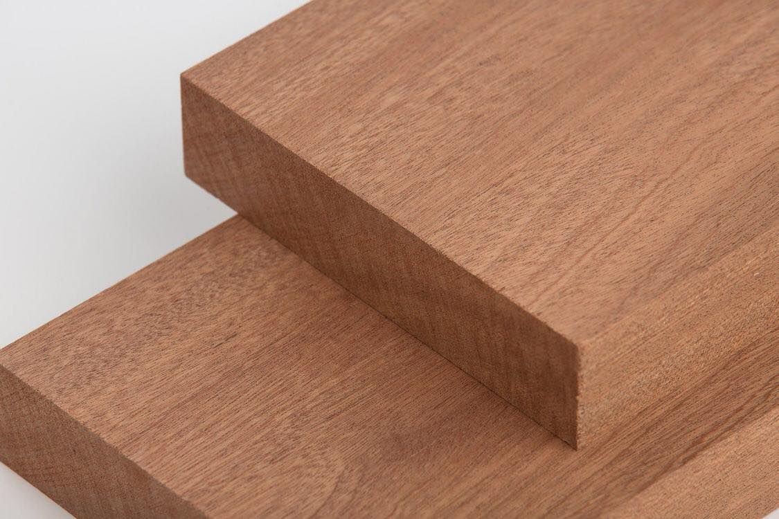 two pieces of wood are stacked on top of each other on a white surface .