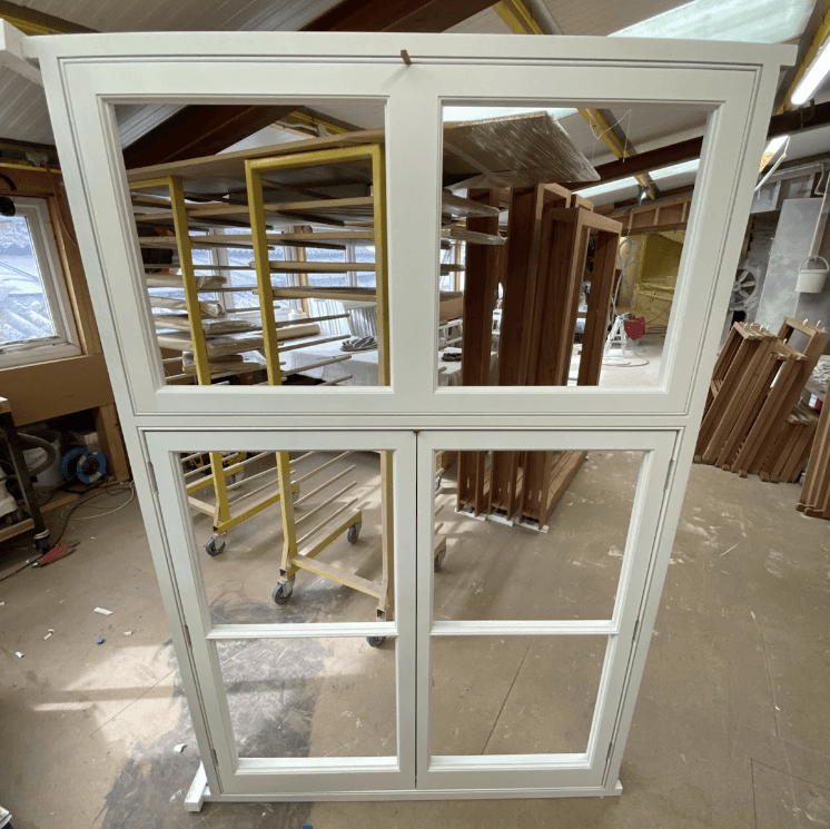 a white timber sash window frame is sitting on a table in a room .