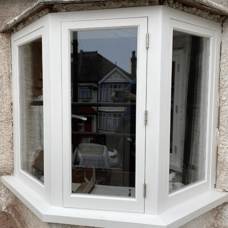 a white timber bay window with a reflection of a house in the window .