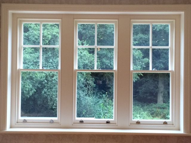 a white sash window with a view of trees outside